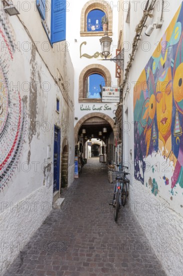 Narrow alley with wall art and bicycles flanked by historic buildings