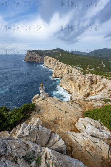 Tourist enjoying the view of steep cliffs by the sea, coastal landscape, cliffs on the Capo Caccia headland, Alghero, Sardinia, Italy