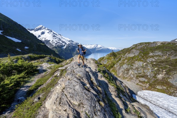 Hikers on Portage Pass, snow-covered mountains and Fjord Passage Canal, near Whittier, Alaska, USA