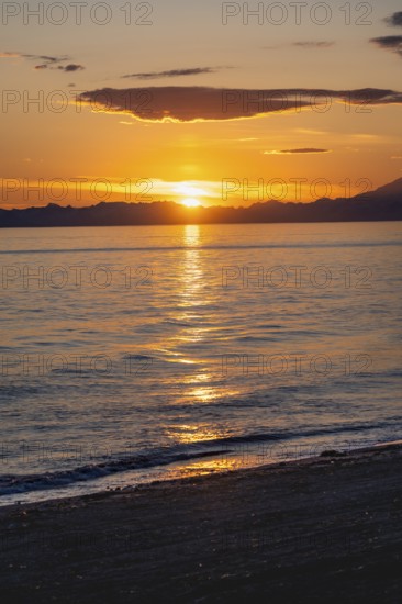 View of Cook Inlet at sunset, picturesque golden light of the midnight sun, mountains of the Aleutian Range, Anchor Point, Anchor River State Recreation Area, Alaska, USA
