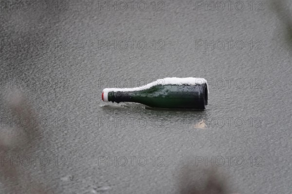 Symbolic picture of garbage in nature, bottle on frozen lake, winter, Germany