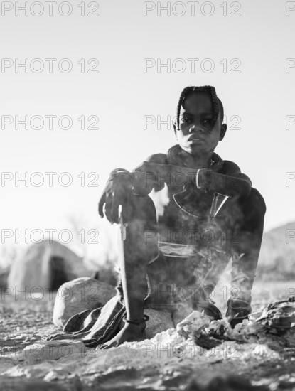 Black and white, Himba child at the fire early in the morning, traditional Himba village, Kaokoveld, Kunene, Namibia