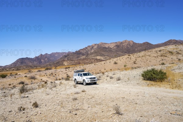 Toyota Hilux off-road vehicle on a sandy track, desert landscape with Brandberg, Erongo, Damaraland, Namibia