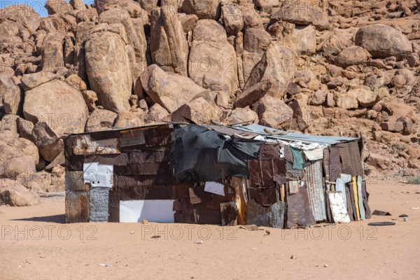 Simple poor huts made of corrugated iron and wood, desert landscape, barren landscape with hills of stacked rocks, Brandberg, Erongo, Damaraland, Namibia