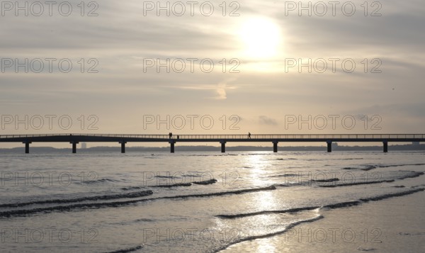 Silhouettes of people on a pier, sunrise, Scharbeutz, 29.11.2025, Scharbeutz, Schleswig-Holstein, Germany