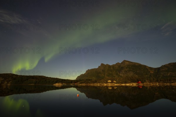 Northern lights are reflected in the fjord in Norway. Aurora Borealis over Festvåg near Bodø, Nordland, Norway