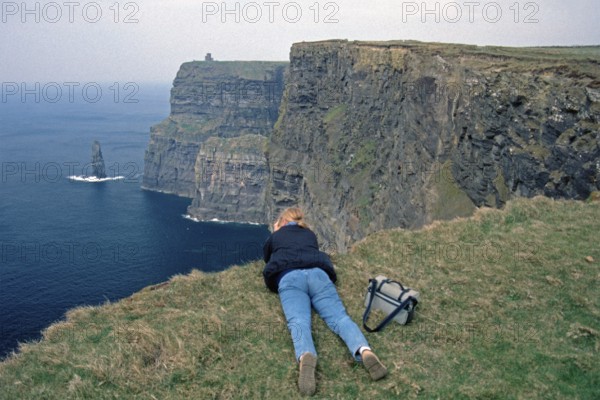 Young woman taking pictures at the edge of a cliff, there was no fence back then, Cliffs of Moher, County Clare, Republic of Ireland, April 1996, vintage, retro, old, historic