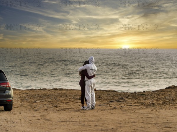Young couple in love standing on the coast of Farol de Cabo Raso lighthouse, São Bras de Sanxete fortress, Cascais, Portugal