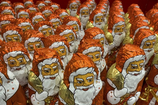 Display on the shelf of chocolate Santa Claus chocolate Santa Claus Santa Claus Santa Claus Santa Claus chocolate Santa Claus chocolate Santa Claus chocolate lice Santa Claus chocolate lice Santa Claus in color red of red staniol paper made of chocolate arranged like army of Santa Claus, Germany