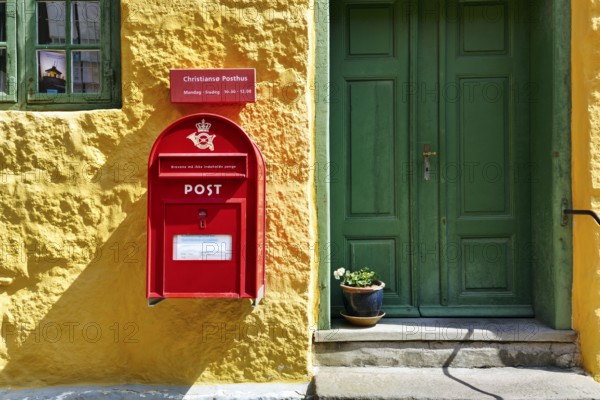 Post office, façade detail, red mailbox with post horn and crown, green wooden door, yellow wall, Christiansø, Christiansö, Ertholmene, Pea Islands, Bornholm, Baltic Sea, Denmark