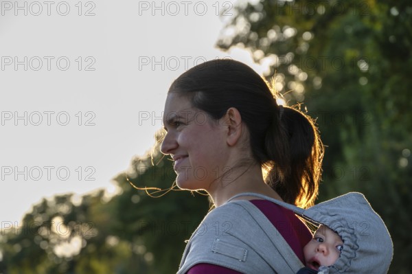 Young mother carrying her baby in a shawl on her back, Othenstorf, Mecklenburg-Western Pomerania, Germany