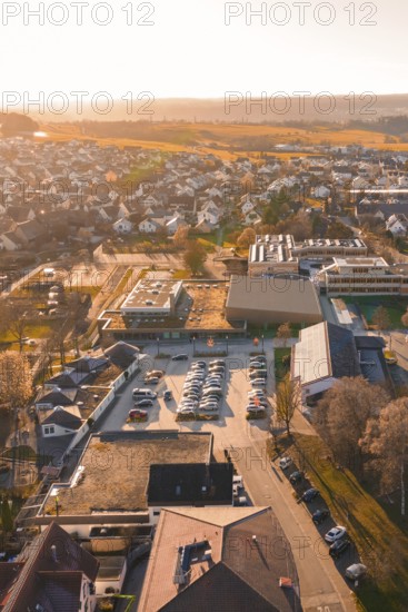 Aerial view of a village at sunset with parked cars and houses, sports center and swimming pool Althengstett, Calw district, Germany