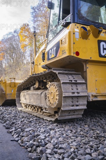 CAT chain tractor on gravel, area in autumn forest during construction, Hermann Hesse Railway track construction, Calw, Germany