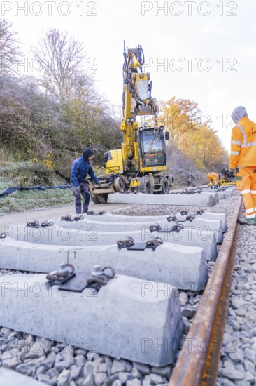 Workers and excavators install new rail ties in an autumn environment, Hermann Hesse Railway track construction, Calw, Germany
