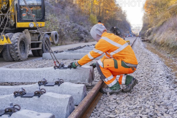 A construction worker wearing glowing safety clothing works on sleepers along the railway line, Hermann Hesse Railway track construction, Calw, Germany