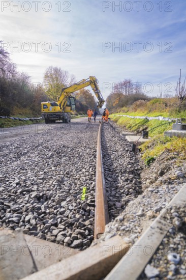 Excavators and workers lay tracks on a construction site on a sunny autumn day, track construction by the Hermann Hesse Railway, Calw, Germany