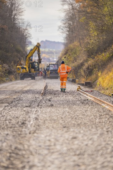 Road construction with construction workers and cranes on a gravel road in autumn, track construction of the Hermann Hesse Railway, Calw, Germany