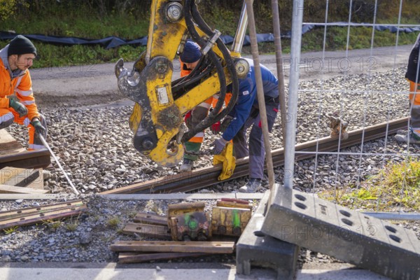 Construction workers install rails on a construction site with heavy equipment, Hermann Hesse Railway track construction, Calw, Germany