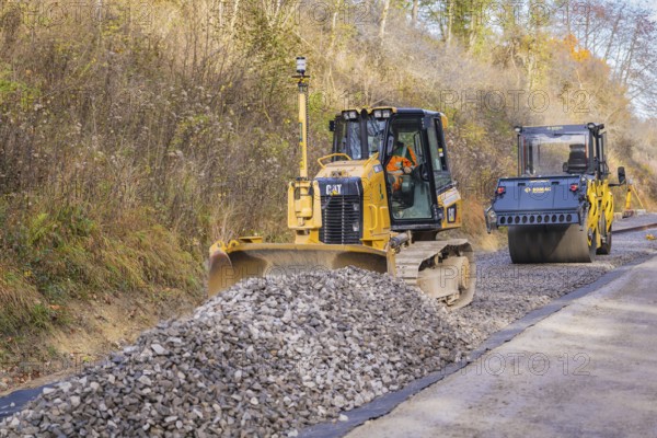 Bulldozer and road roller processing ballast on a construction site, Hermann Hesse Railway track construction, Calw, Germany