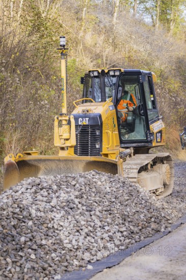 Bulldozer moves gravel on a construction site surrounded by autumn leaves, Hermann Hesse Railway track construction, Calw, Germany