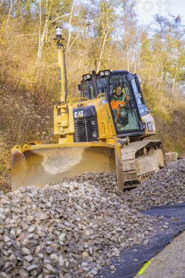 Bulldozer with a large shovel moves gravel on a construction site, track construction of the Hermann Hesse Railway, Calw, Germany