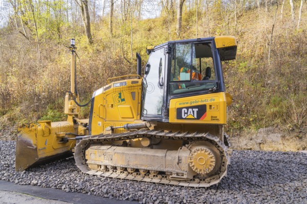 CAT chain tractor on gravel, autumn vegetation during construction work in the background, Hermann Hesse Railway track construction, Calw, Germany