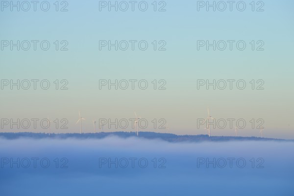 Wind turbines on a hill with fog in the foreground and blue sky, Miltenberg, Spessart, Bavaria, Germany