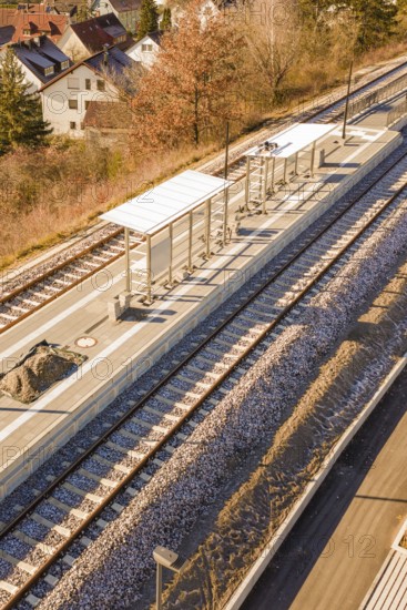 Station with platforms and tracks, surrounded by autumn leaves and houses, seen from a bird's eye view, new Hermann Hessebahn station, Ostelsheim, Calw district, Germany