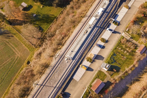 View from above of a train station with an adjacent street and autumnal greenery in the area, new Hermann Hessebahn station, Ostelsheim, Calw district, Germany