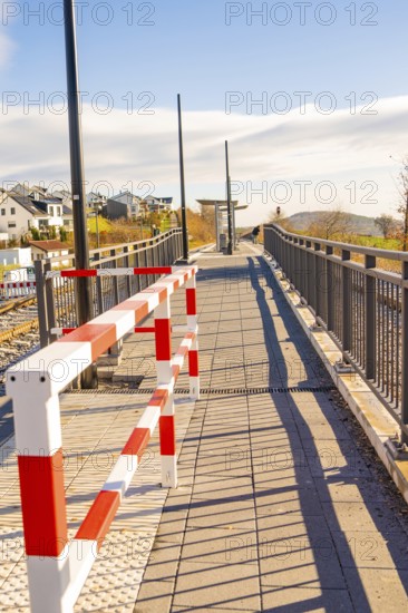 Footbridge with modern barrier and cast shadows in sunshine, new Hermann Hessebahn railway station, Ostelsheim, Calw district, Germany