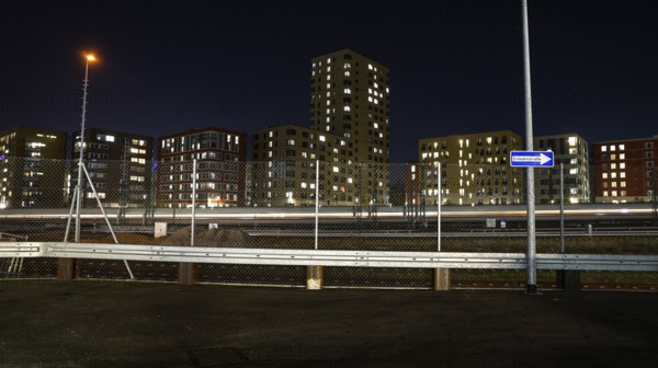 One way street on the fence, behind it a passing ICE train, illuminated apartments in a new housing development, Berlin, 23.11.2025, Berlin, Berlin, Germany