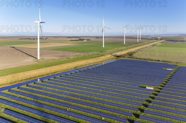 Aerial view over hybrid power plant combing solar photovoltaic modules and wind turbines, North Frisia, Schleswig-Holstein, Germany