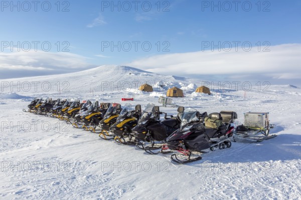 Snowmobiles, snow scooters at Arctic expedition camp with tents protected by tripwire fence against polar bears at Mohnbukta, Spitsbergen, Svalbard