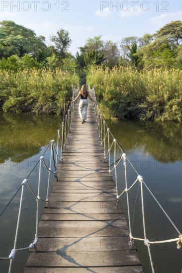 Toruist on the Kavango River, suspension bridge at Camp Kwando, Zambezi region, Caprivi Strip, Namibia