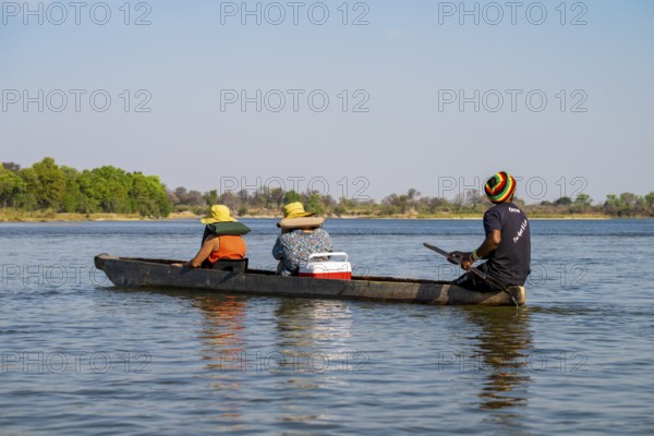 Tourists in a Mokoro, dugout boat on the Okavango River, Caprivi Strip, Namibia