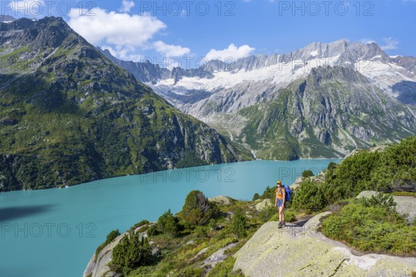 Female mountaineer in front of picturesque mountain landscape, turquoise-blue mountain lake Göscheneralpsee, Dammastock and Damma glacier, Göscheneralp, Canton of Uri, Switzerland