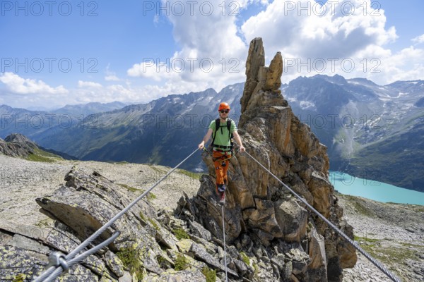 Crocodile rock formation, mountaineer on rope bridge in the Crocodile Mountain Lake via ferrata on Bergseeschijen-Vorbau, Göscheneralp, Canton of Uri, Switzerland