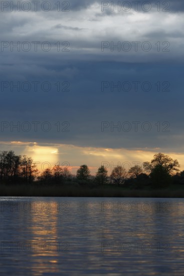 Sunset over the river with dramatic clouds, Peenetal nature park Park, Mecklenburg-Western Pomerania, Germany