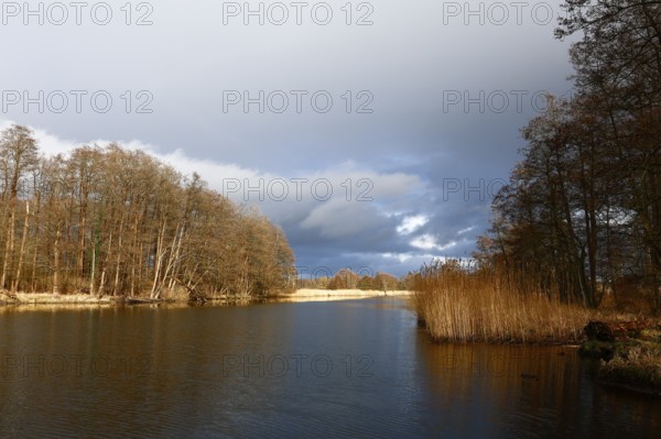 Spring atmosphere with cloudy skies and sunshine over a quiet river, Peenetal nature park Park, Mecklenburg-Western Pomerania, Germany