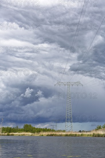 A large power pole in a vast landscape under dramatic clouds, Peenetal nature park Park, Mecklenburg-Western Pomerania, Germany