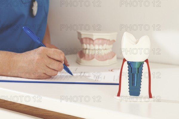 A dentist in a blue uniform studies patient information and prepares for treatment in a modern dental office