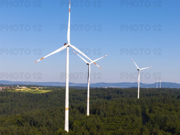 Wind turbines tower over a wooded landscape, dominated by clear skies, near Schorndorf, Remstal, Baden-Württemberg, Germany