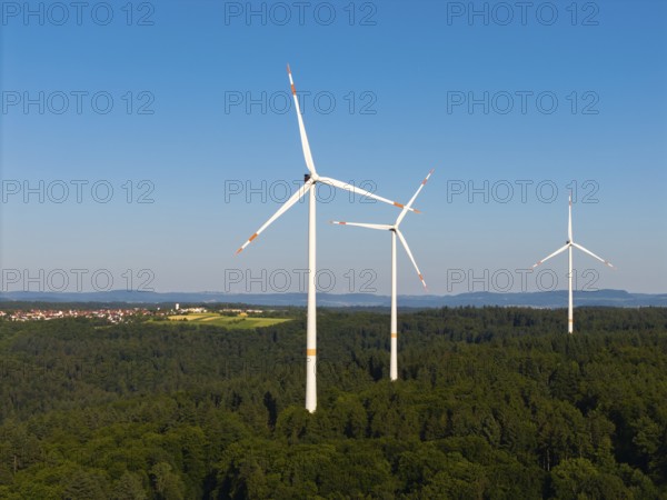 Three wind turbines above a dense forest area under a clear sky, near Schorndorf, Remstal, Baden-Württemberg, Germany