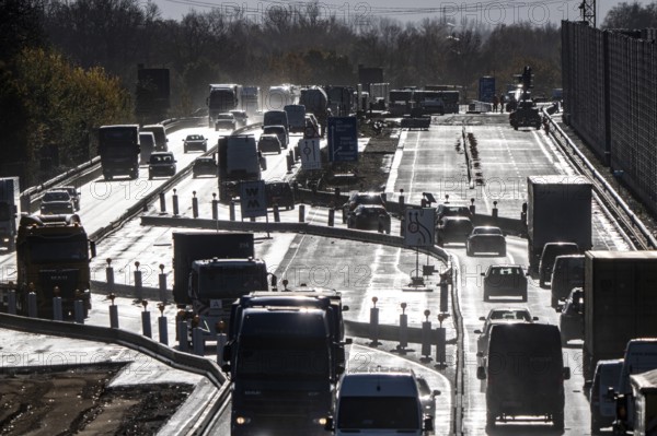 Highway construction site, the A57 is extended to 6 lanes on the section between the Meerbusch motorway junction and the Oppum junction, traffic runs parallel to 2 narrowed lanes, wet road after rain shower, Krefeld, North Rhine-Westphalia, Germany