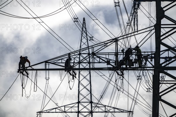 Work on a 380 kV high-voltage overhead line, new construction, along the A57 motorway, near Meerbusch, workers on the boom of the high-voltage pylon, North Rhine-Westphalia, Germany