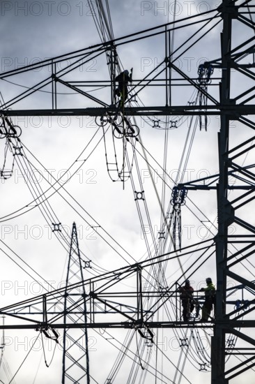 Work on a 380 kV high-voltage overhead line, new construction, along the A57 motorway, near Meerbusch, workers on the boom of the high-voltage pylon, North Rhine-Westphalia, Germany
