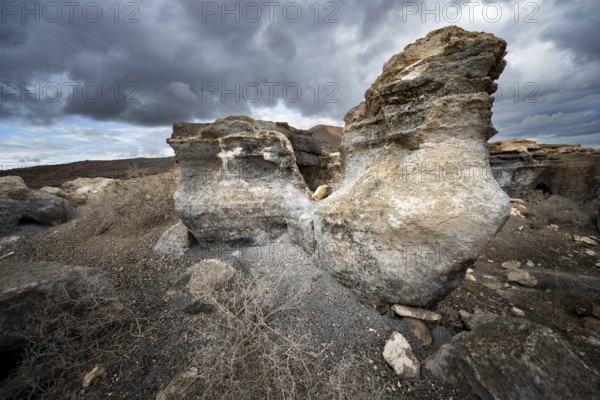Eroded rock formations in volcanic landscape with dramatic cloudy skies, Ciudad Estratificada or Los Roferos, Antigua Rofera de Teseguite, Lanzarote, Canary Islands, Spain