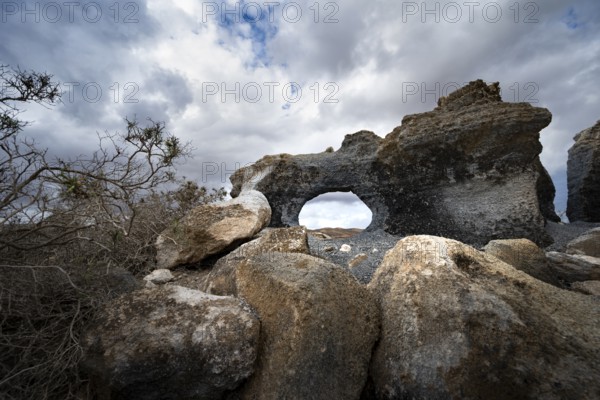 Eroded rock formations with rock tunnels, volcanic landscape with dramatic cloudy skies, Ciudad Estratificada or Los Roferos, Antigua Rofera de Teseguite, Lanzarote, Canary Islands, Spain