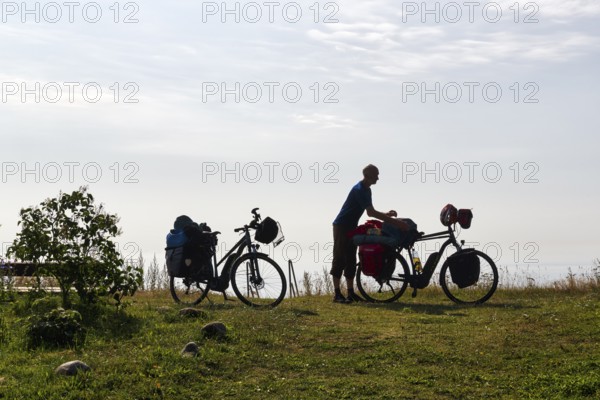 Two e-bikes with luggage bags, cyclist taking a break, back light, Ystad, Sweden