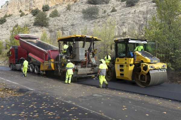 Asphalt road construction team of workers resurfacing tarmac in rural area, near Albarracin, Teruel province, Aragon, Spain